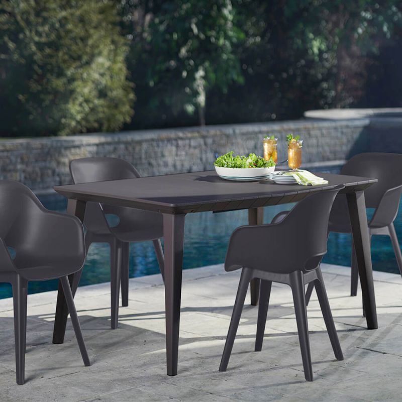 Ensemble de table de jardin sombre avec quatre chaises confortables sur une terrasse à côté d'une piscine