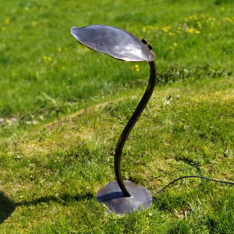 Lampada da giardino nera curva su prato verde sotto il sole