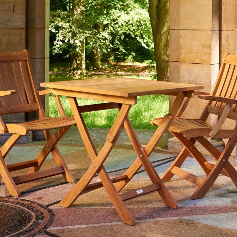 Petite table carrée en bois avec quatre chaises pliantes assorties sur une terrasse de jardin