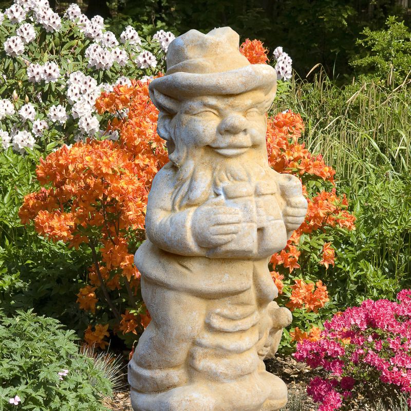 Nain de jardin en pierre tenant un cadeau entouré de fleurs colorées
