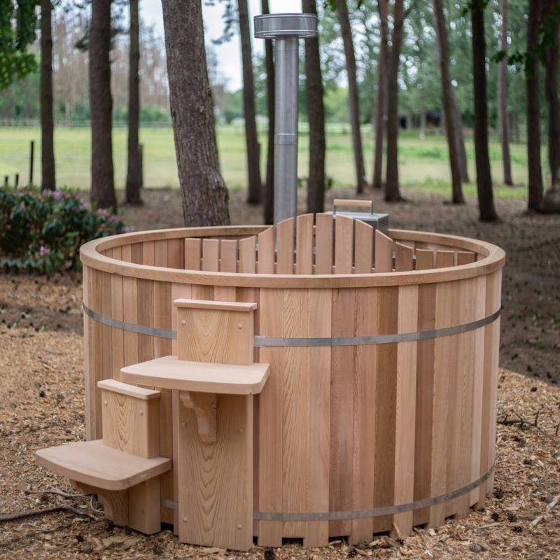 Vasca rotonda in legno da giardino con piccola scala a tre gradini e bosco sullo sfondo