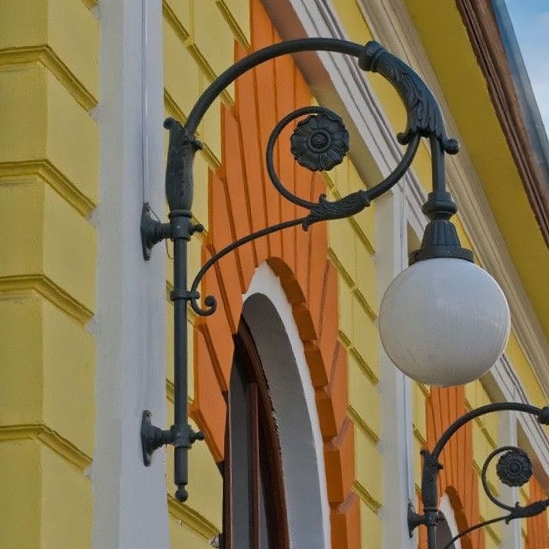 Lanterne murale noire historique avec globe blanc sur façade jaune et orange