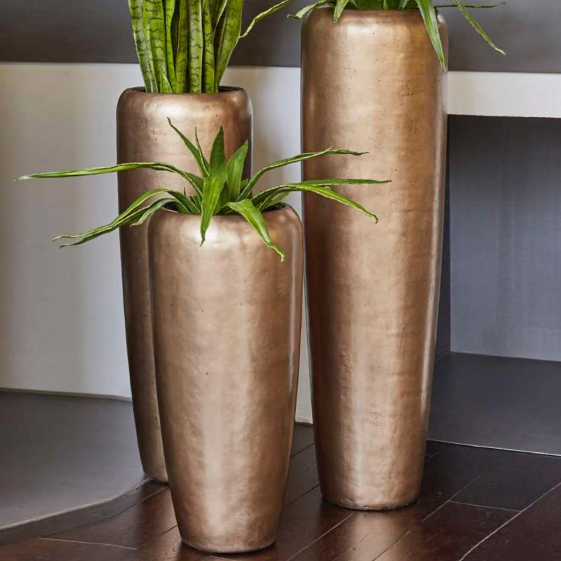 Due grandi vasi color bronzo con piante verdi all'interno