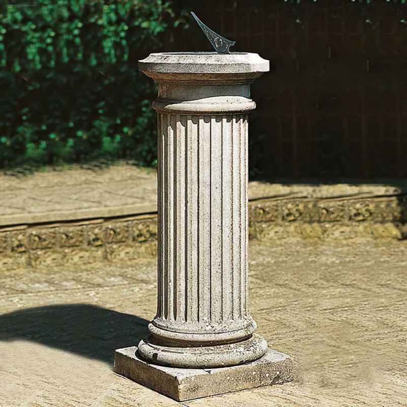 Meridiana vintage in pietra su una colonna in un giardino con vegetazione