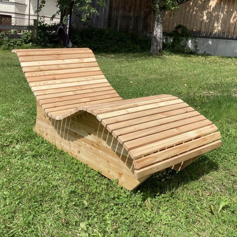 Chaise longue en bois au design ergonomique sur pelouse verte dans un jardin