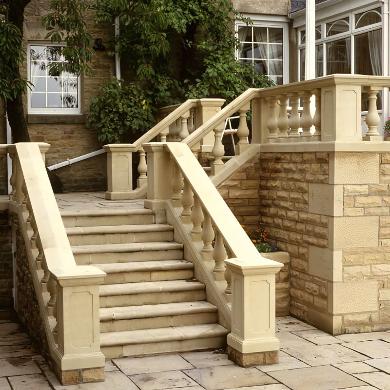 Large escalier en pierre avec rampe en balustres, entouré de murs de jardin et de plantes