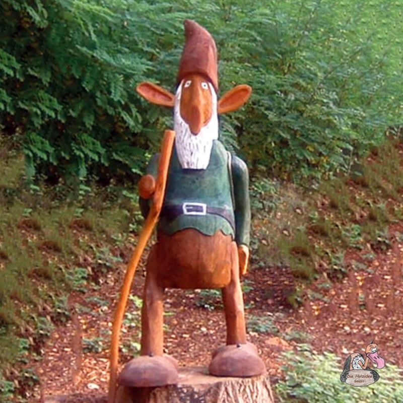 Nain de jardin en bois avec bonnet rouge et chemise verte sur tronc d'arbre dans le jardin