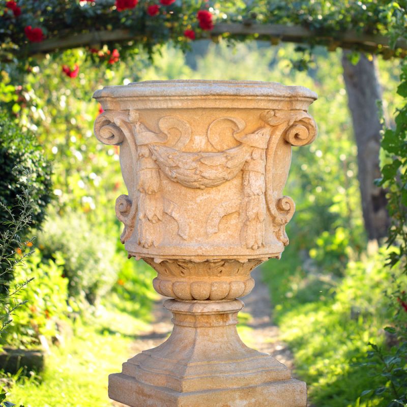 Urne en pierre avec des reliefs décoratifs dans un jardin ensoleillé