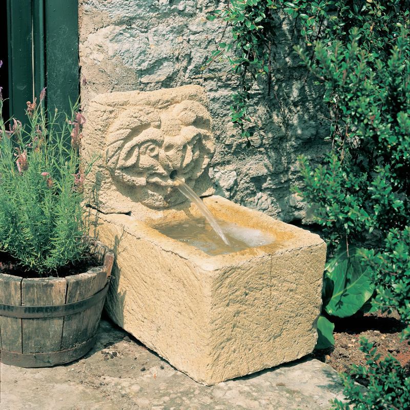 Fontaine de jardin rustique en pierre avec eau courante dans le jardin