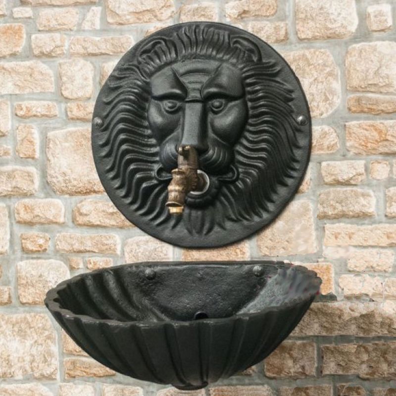 Fontana da giardino testa di leone nera con rubinetto, montata su muro di pietra con catino nero in metallo