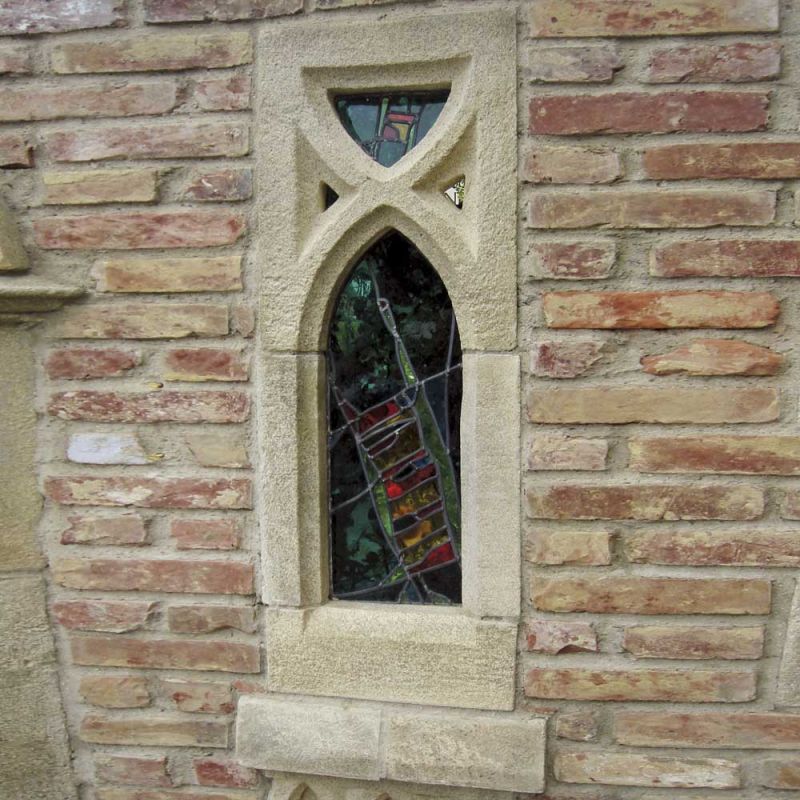 Meridiana in pietra con vetri colorati inserita in un muro di mattoni per decorazione da giardino