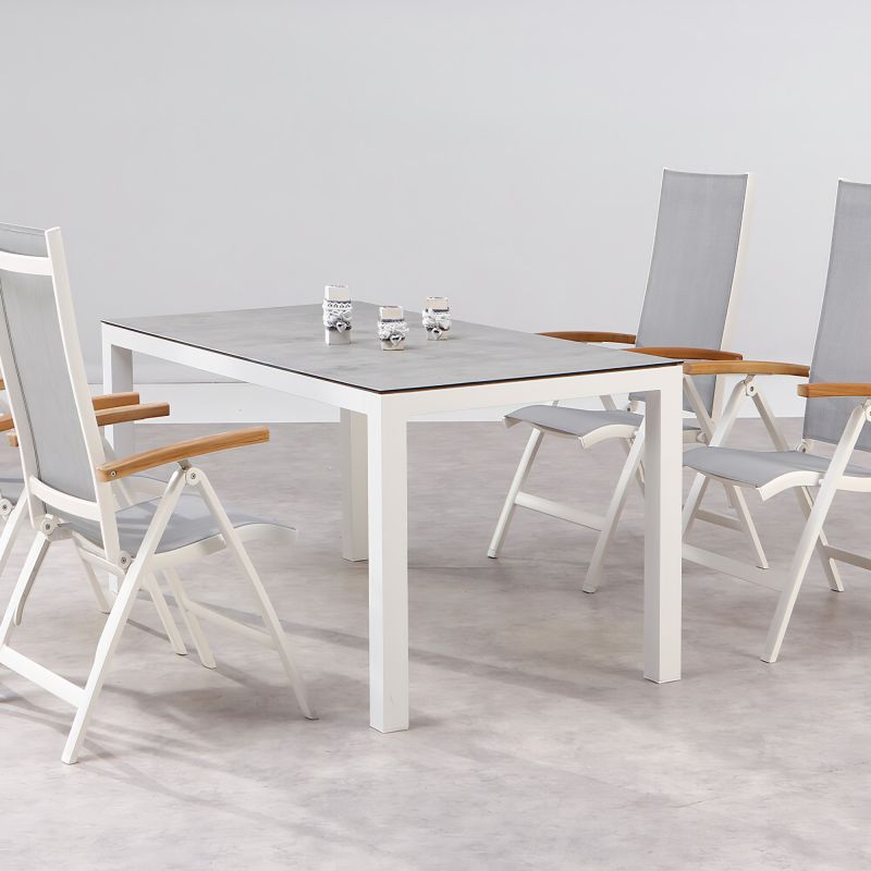 Tavolo da giardino rettangolare bianco con quattro sedie da giardino bianche e in legno chiaro su pavimento grigio
