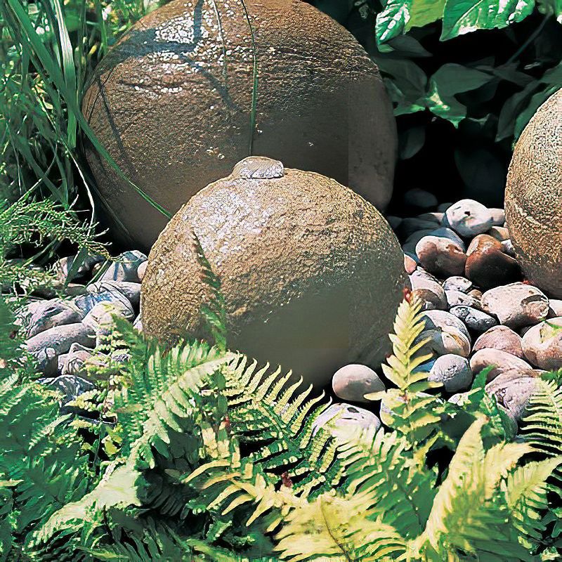 Due sfere di fontana in giardino su ciottoli circondate da felci