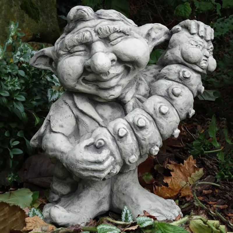 Décoration de jardin expressive : figure de troll en pierre tenant une grande chenille dans le jardin
