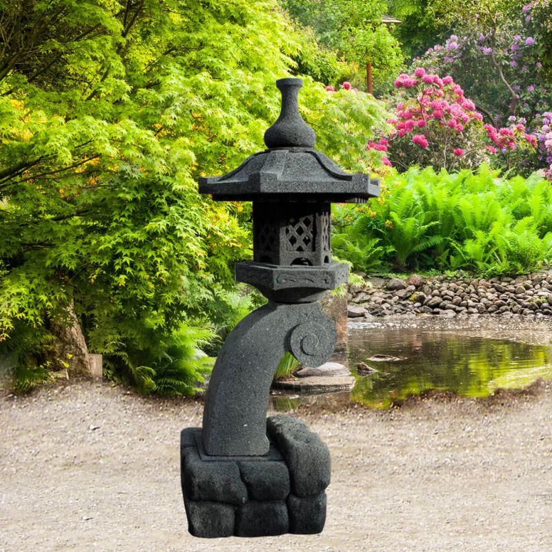 Lanterne noire en pierre au design asiatique dans un jardin vert avec étang et fleurs