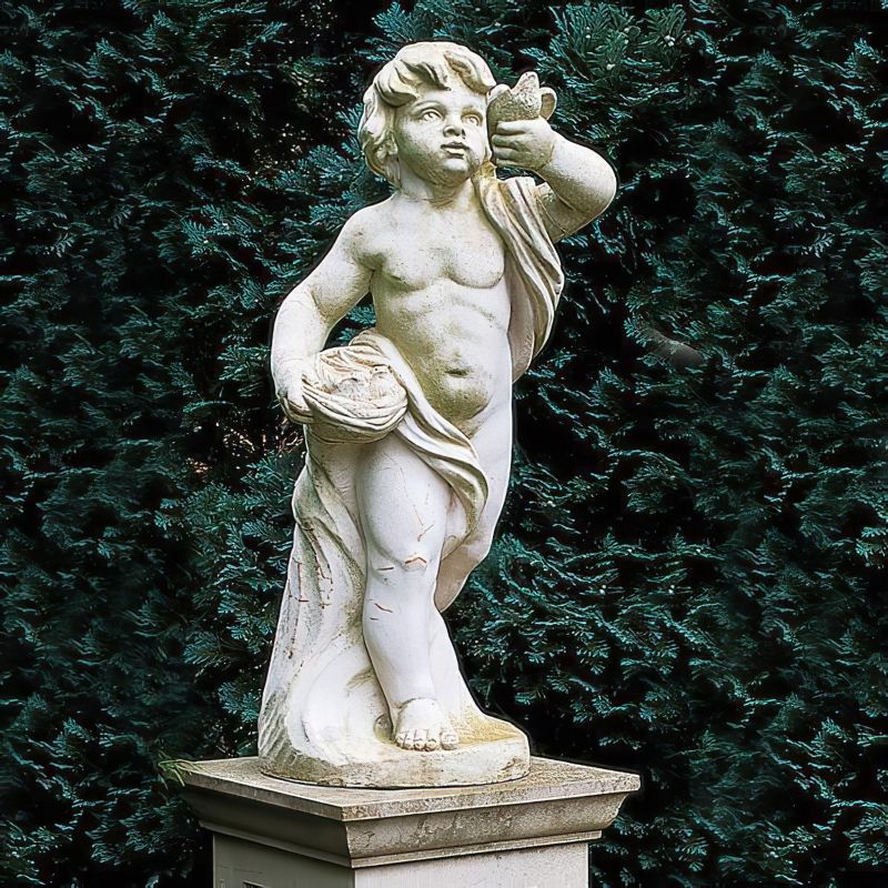 Statua bianca in marmo di un bambino nudo con un cesto, circondato da arbusti sempreverdi