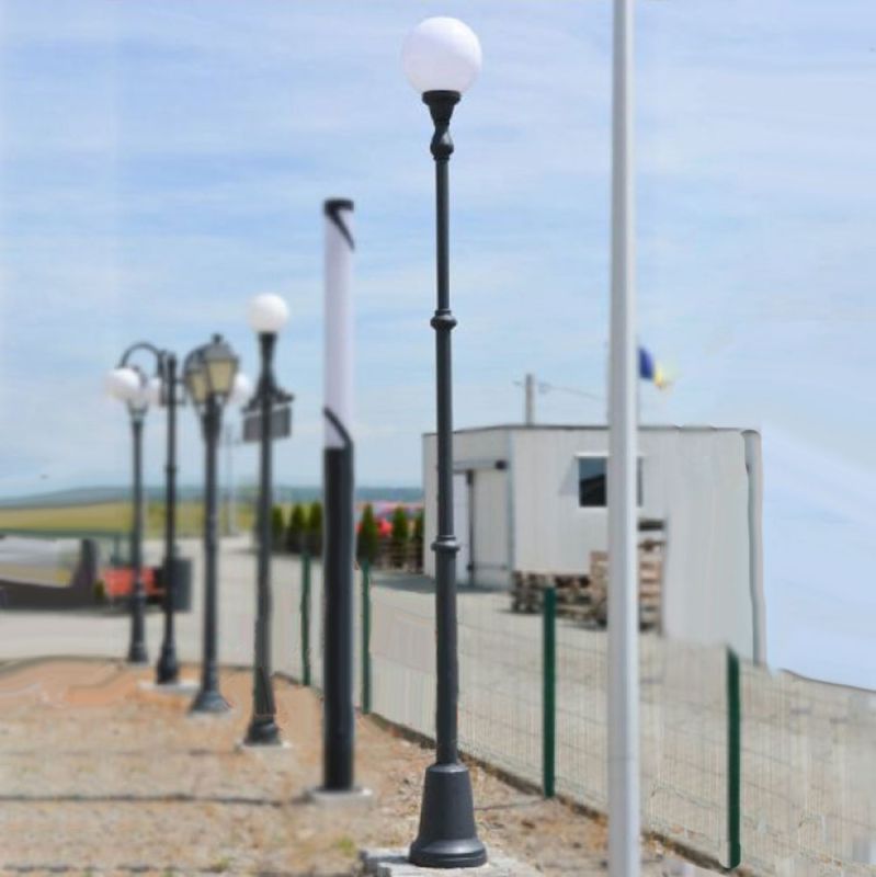 Lampadaires de jardin noirs avec globe en verre blanc le long d'un chemin ensoleillé