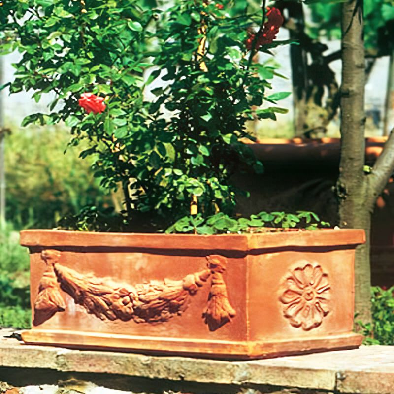Jardinière rectangulaire en terre cuite avec décor floral dans un jardin sur un muret