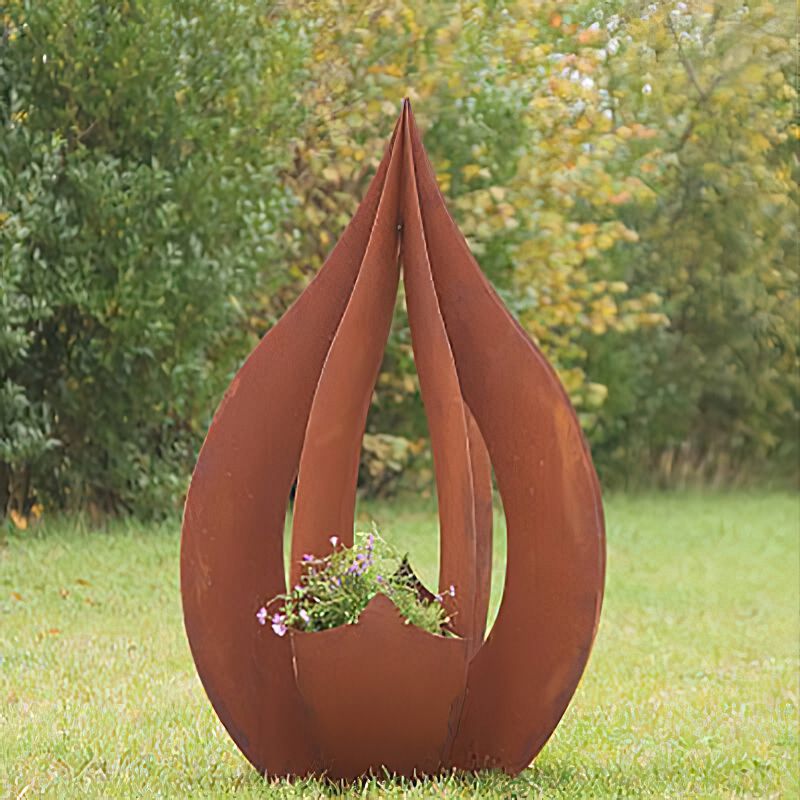 Décoration de jardin en métal rouillé en forme de goutte sur herbe verte avec des plantes à l'intérieur