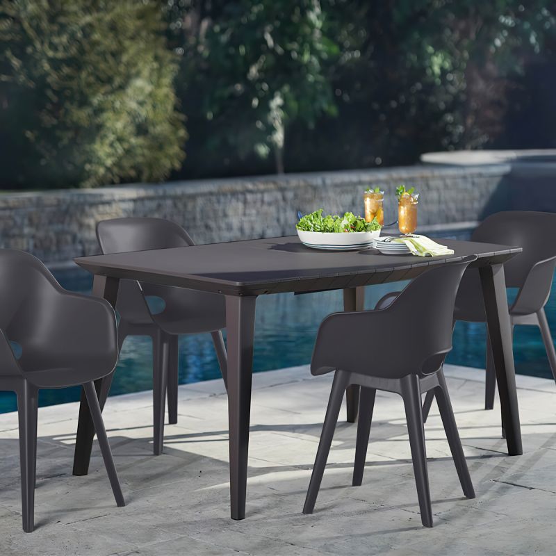Elegante tavolo da giardino con quattro sedie accanto a una piscina, circondato da muro da giardino e piante