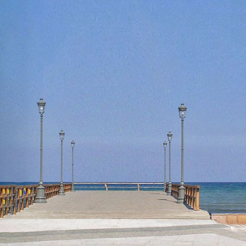 Jetée en bois avec lampadaires menant à la mer sous un ciel bleu