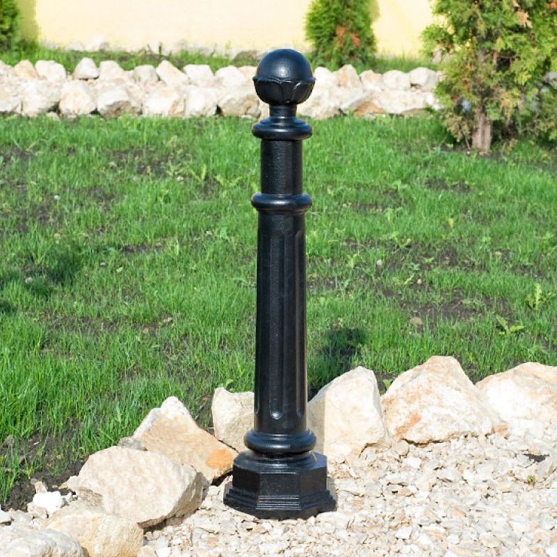 Borne de jardin noire élégante en métal sur un chemin de gravier devant une pelouse verte