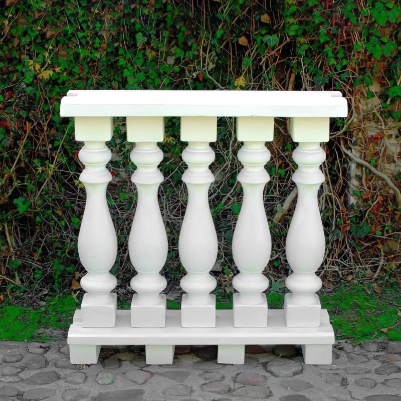 Balustrade blanche en pierre devant une haie verte dans le jardin