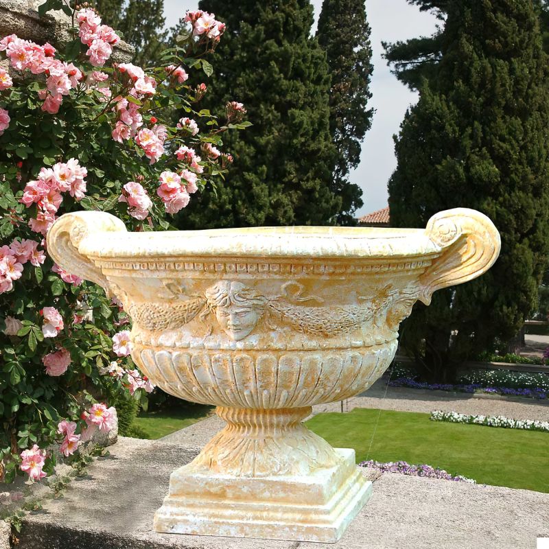 Grande fontana decorativa in pietra in un giardino curato con rose e cipressi