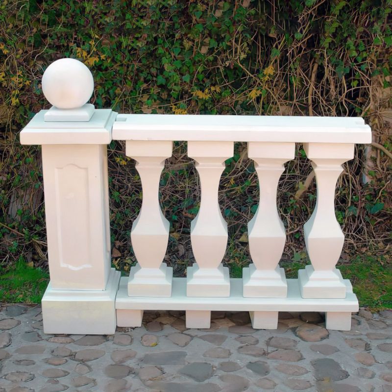 Balustrade de jardin blanche en pierre avec boule sur pilier devant une haie