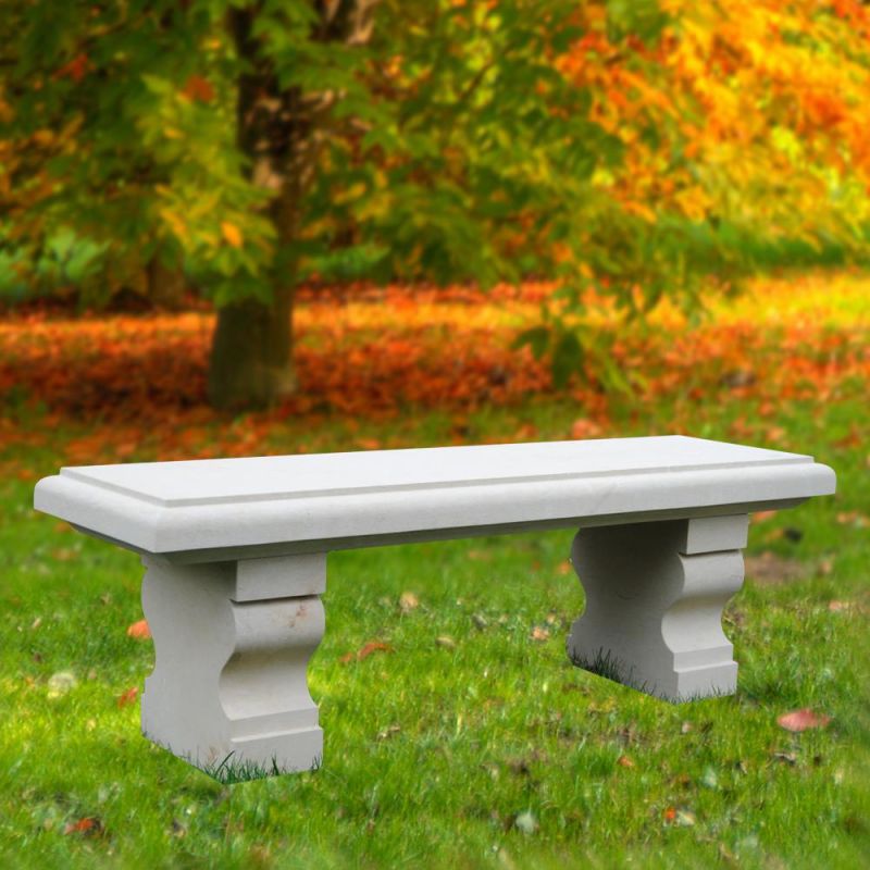 Banc en pierre blanche classique sur herbe verte avec des feuilles d'automne colorées en arrière-plan