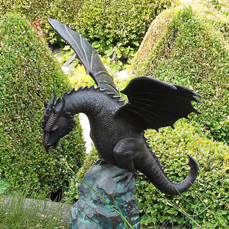 Figure de dragon noir en métal dans un jardin verdoyant