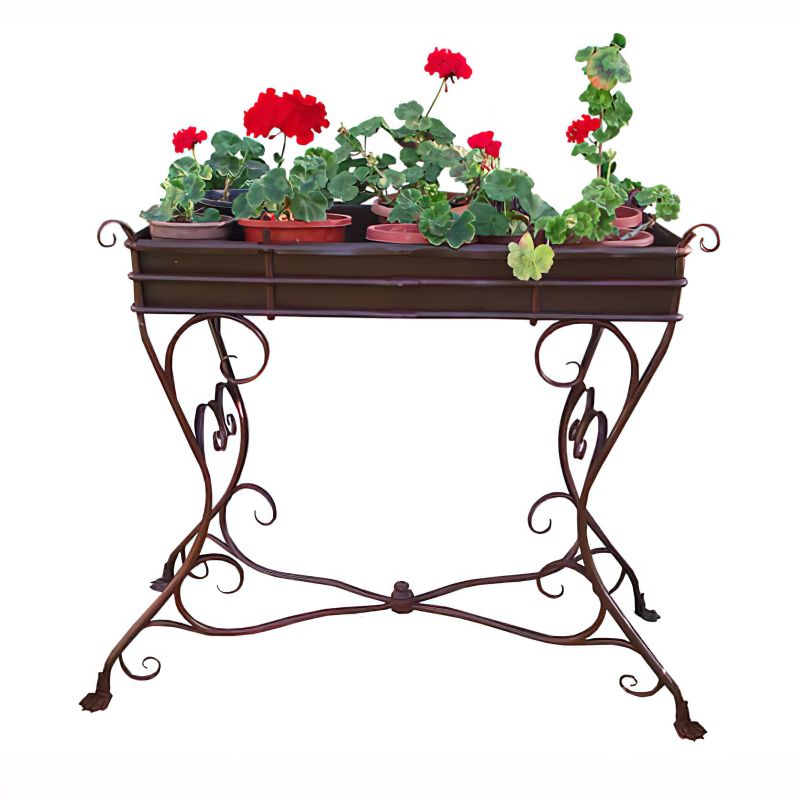 Table de jardin en métal brun avec des pieds décoratifs et des fleurs rouges en pots