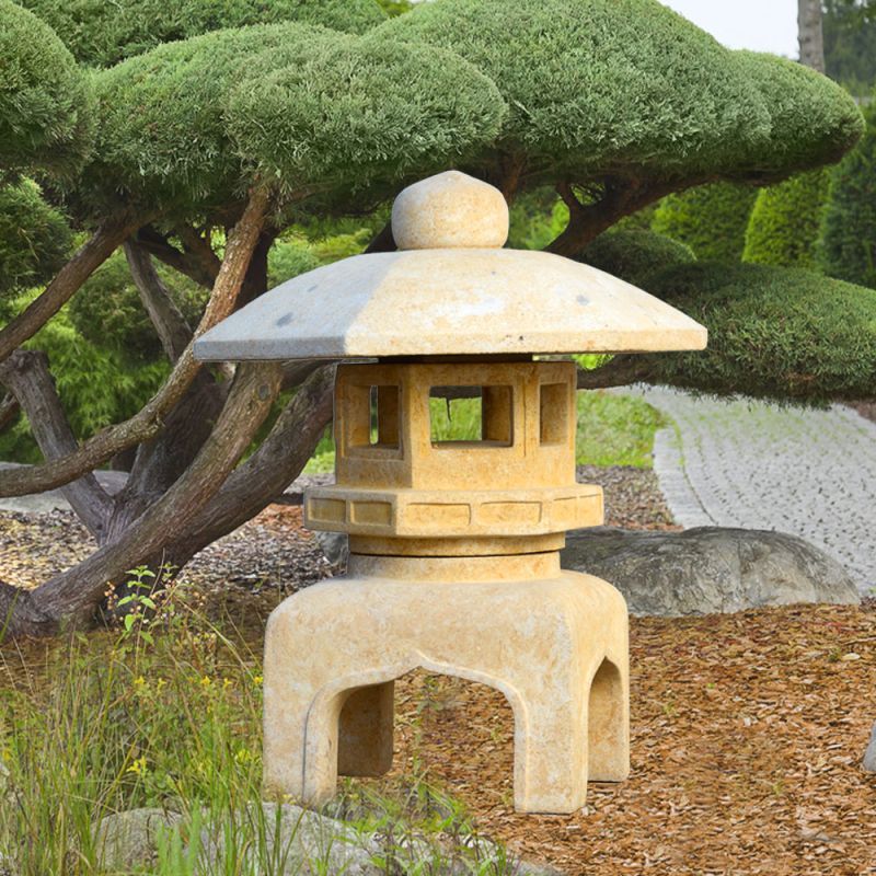 Lanterne de jardin beige à côté d'un arbre décoratif dans un jardin vert