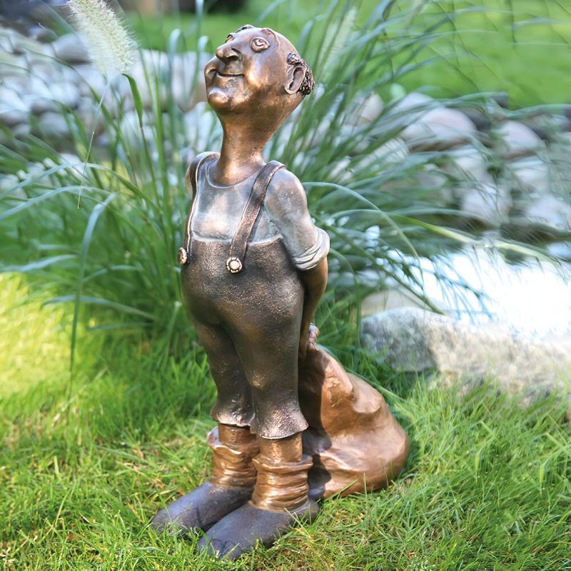 Décoration de jardin en bronze montrant une statue souriante d'un homme dans un jardin