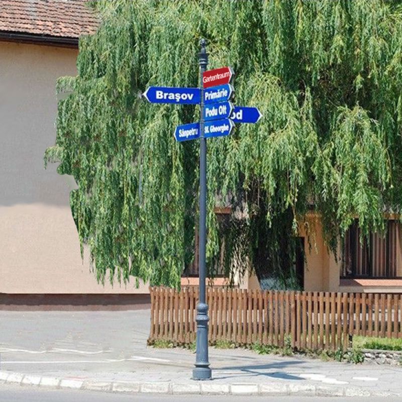 Cartello stradale in metallo con targhe blu davanti a un albero verde e una recinzione in giardino