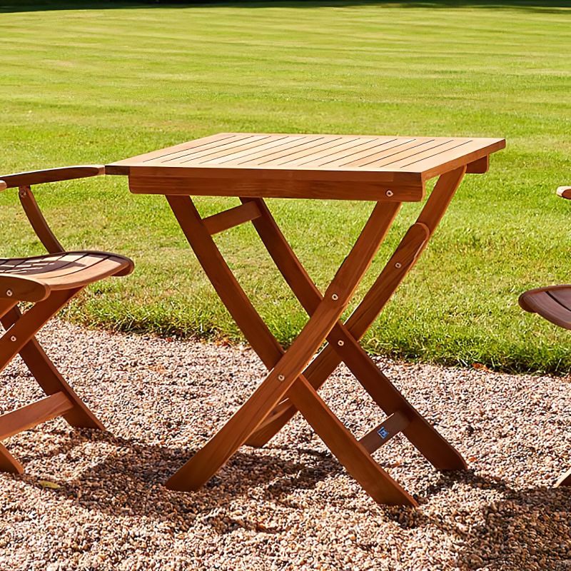 Petite table de jardin en bois avec deux chaises en bois sur un chemin de gravier devant une pelouse bien entretenue