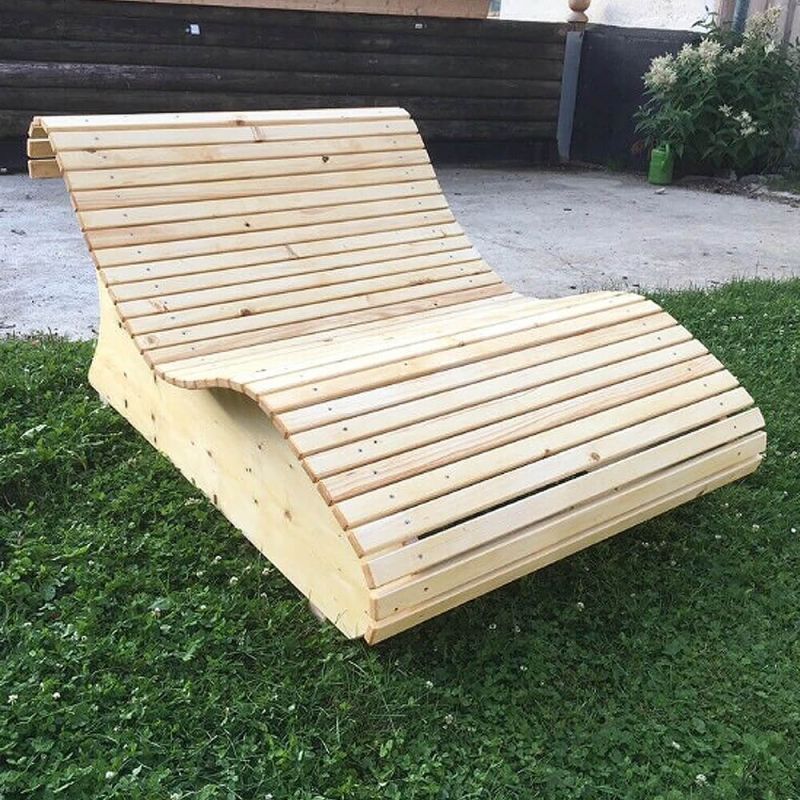 Lettino da giardino curvo in legno su prato verde
