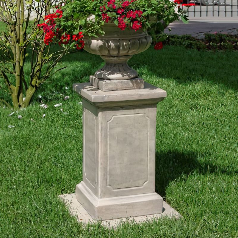 Socle lourd en pierre pour jardin avec arrangement floral rouge sur pelouse verte