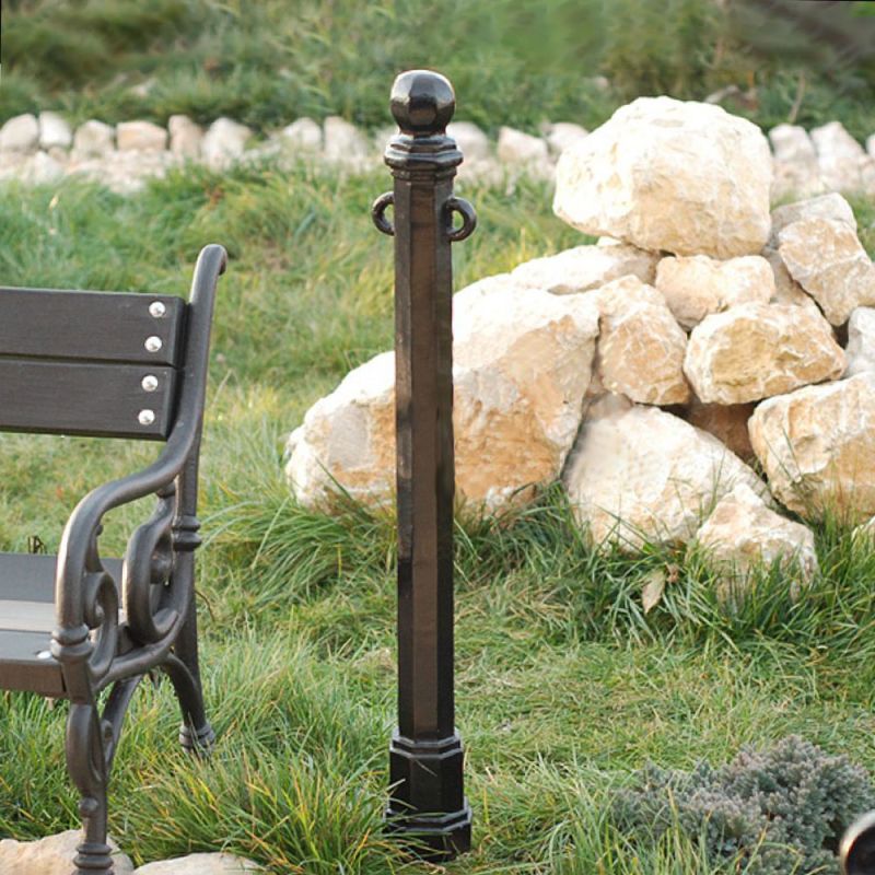 Poteau en métal noir dans un jardin avec des pierres et un banc de jardin