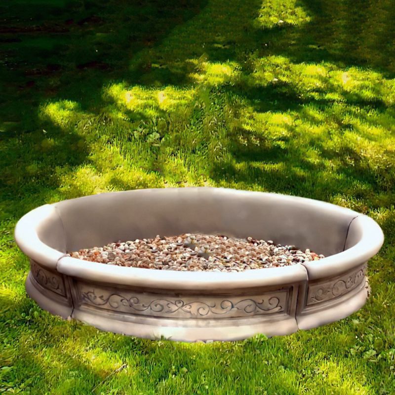 Recinto di sabbia rotondo con bordo decorato su prato verde nel giardino