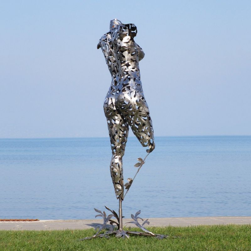 Sculpture moderne en métal d'une femme comme décoration de jardin avec la mer en arrière-plan
