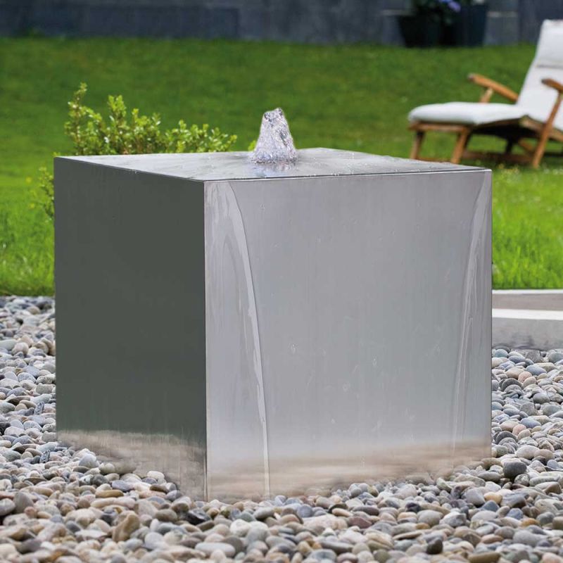 Fontana da giardino cubica con getto d'acqua su letto di ciottoli