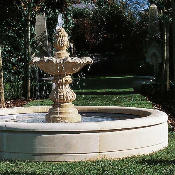 Grande fontana in pietra beige con un rigoglioso giardino sullo sfondo
