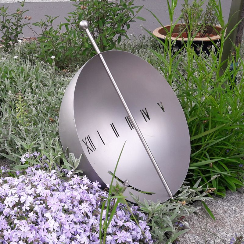 Cadran solaire rond avec chiffres romains dans une décoration de jardin avec fleurs et plantes