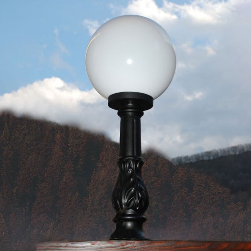 Colonne de jardin noire décorative avec boule en verre blanc devant un ciel nuageux