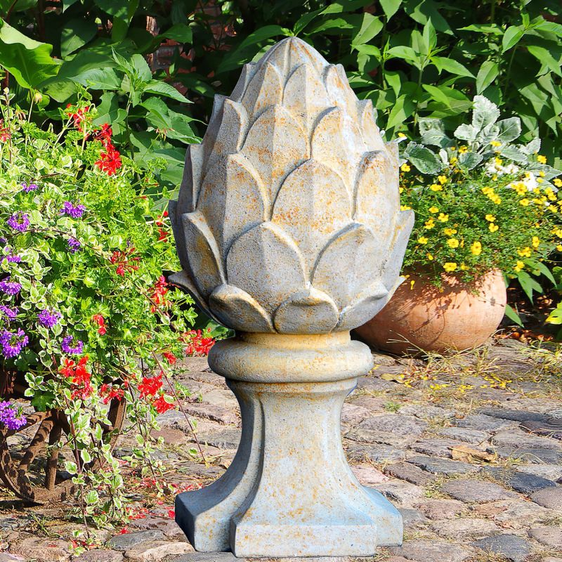 Scultura in pietra a forma di carciofo come decorazione da giardino esclusiva su lastricati circondata da fiori