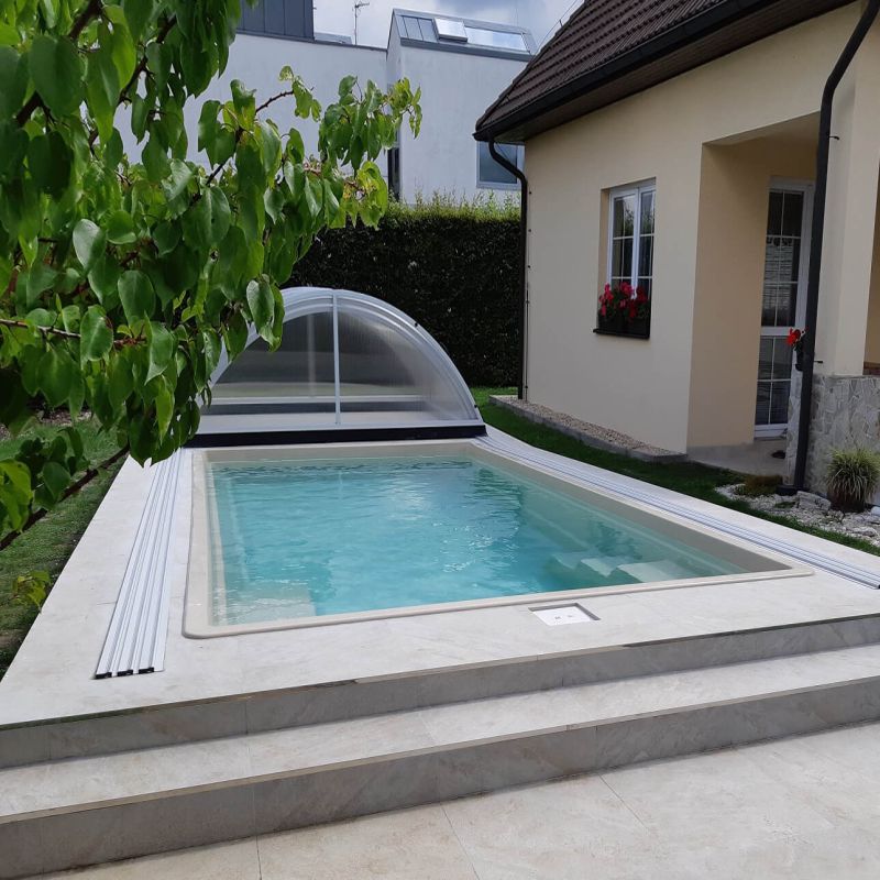 Moderner rechteckiger Pool mit klarem Wasser neben einem Haus im Garten