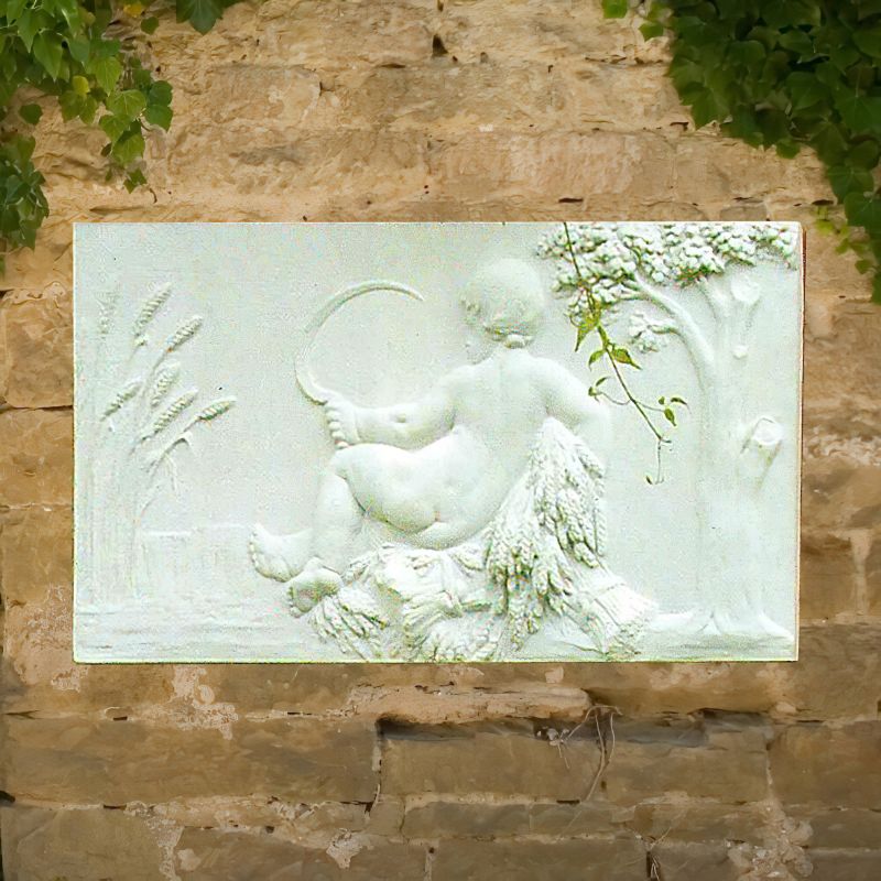 Rilievo bianco in pietra di un bambino seduto con spighe davanti a un muro di pietra