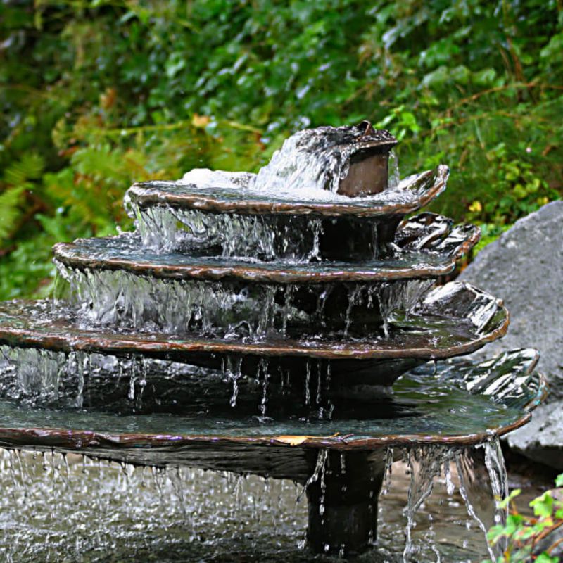 L'eau coule sur plusieurs niveaux ronds d'une fontaine décorative dans un jardin