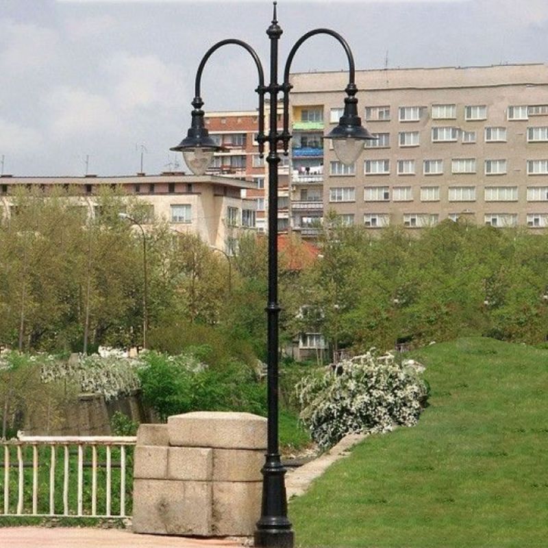 Lampada da giardino a due luci in metallo davanti a condomini in un parco verde